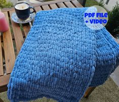 a blue blanket sitting on top of a wooden table next to a cup of coffee