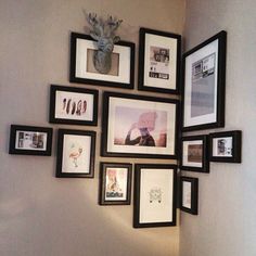 a bunch of framed pictures on the wall above a toilet in a room with white walls