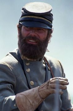 an image of a man with a beard and uniform looking at the camera while wearing a hat