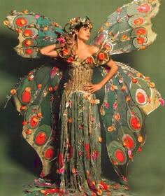 a woman in a costume made out of flowers and leaves with her hands on her hips