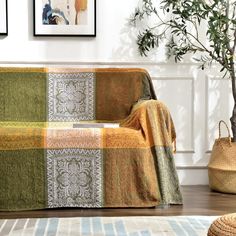 a living room with a couch covered in a blanket and potted plant next to it