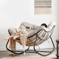 a woman laying in a rocking chair with a blanket on it's back and her legs crossed