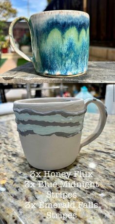 two mugs sitting on top of a table next to each other with different designs