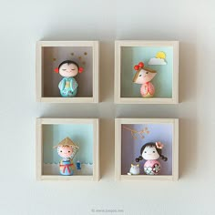 four little dolls are placed in small wooden cubes on a white surface, each with an individual's own doll