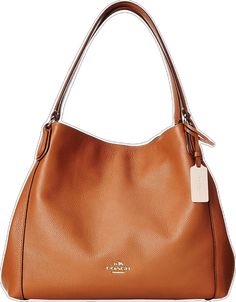 a brown coach purse with a tag on the front and bottom part of it's handle