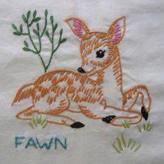 an embroidered deer sits in the grass with its name written on it's back