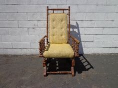 an old rocking chair sitting in front of a white brick wall with no one on it