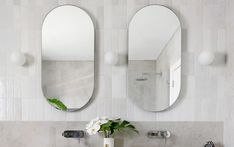 a bathroom sink with two mirrors above it and a vase with flowers on the counter