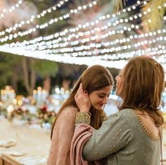 two women standing next to each other with lights in the background