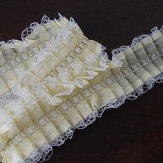 two pieces of white lace sitting on top of a wooden table next to each other