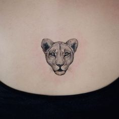 a woman's chest with a small tattoo of a lion head on her left side