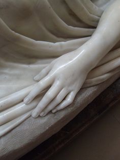 a close up of a person's hands on top of a bed with sheets