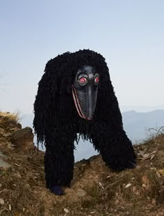 a large black animal with red eyes standing on top of a hill