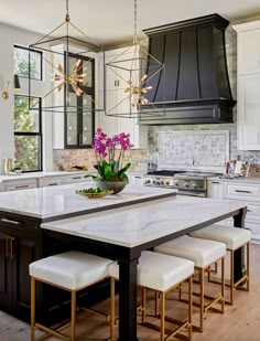 a large kitchen with an island and marble counter tops in front of a stove top oven