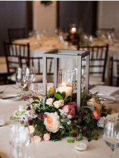 a centerpiece with flowers and candles on a table at a wedding reception in an elegant setting