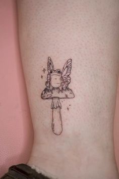 a small tattoo on the ankle of a girl with a mushroom and angel wings above her head