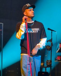 a man standing in front of a microphone on top of a stage holding a red pole