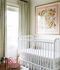 a baby's room with a white crib, pink rocking horse and floral curtains