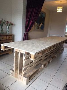 a table made out of wooden pallets sitting on top of a white tiled floor