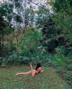 a naked woman laying in the grass near trees