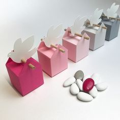 four boxes with paper doves on them and some candy in the bottom one is pink