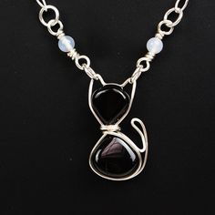 a black and white necklace on a silver chain with blue glass bead around it