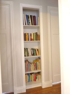 a bookshelf filled with lots of books on top of a hard wood floor