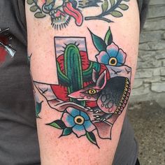 a person with a tattoo on their arm holding a cell phone and cactus in the background