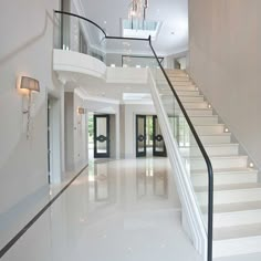 a white staircase with glass railing and chandelier