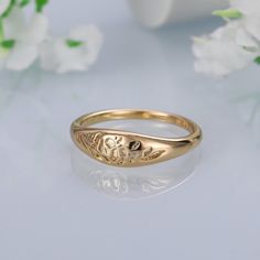 a close up of a gold ring on a white surface with flowers in the background