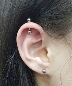 a close up of a person with an ear piercing on their left side, and two balls in the middle