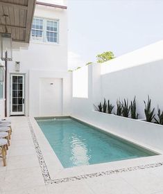 an outdoor swimming pool surrounded by white walls