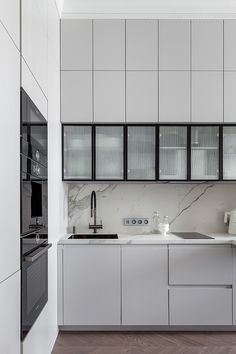 a kitchen with white cabinets and marble counter tops