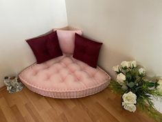 a pink couch sitting on top of a hard wood floor next to a vase with white flowers