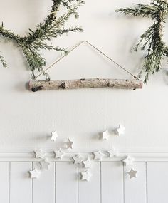 some white stars are hanging on the wall next to a branch and other decorations in front of it