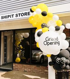 an entrance to a shop with balloons in the shape of yellow and black flowers on it