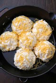 four biscuits covered with cheese in a cast iron skillet