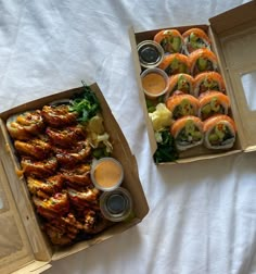 two boxes filled with different types of food on top of a white sheet covered table