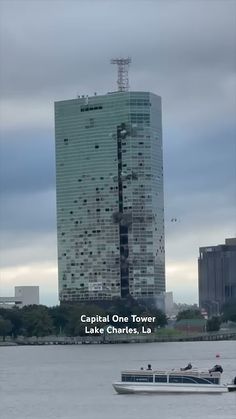 there is a boat that is in the water near a tall building with many windows