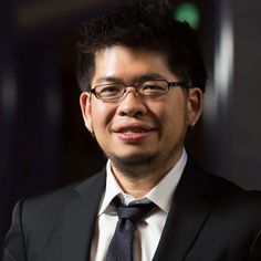 a man in a suit and tie smiling for the camera