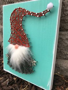 a string art piece with a santa clause hat on it's head and white hair