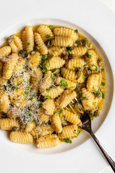 a white plate topped with pasta and parmesan cheese