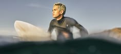 a man in a wet suit holding a surfboard