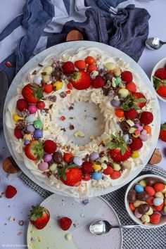 a cake decorated with strawberries, chocolates and other candies on a table