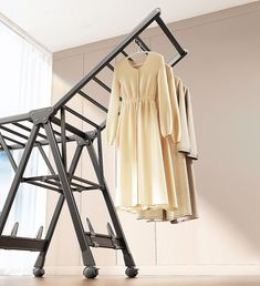 an ironing board and dress hanging on a clothes rack in front of a window