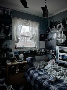 an unmade bed sitting next to a window in a room with pictures on the walls