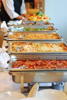 several trays of food are lined up on a buffet table, ready to be served