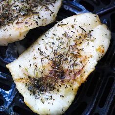 two pieces of chicken on top of a grill with seasoning sprinkles