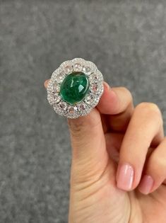 This one-of-a-kind natural emerald ring features an exceptional display of craftsmanship and imaginative design, perfect for those who love the incredible color combination of high-quality green Emerald and diamond. 8.91 carat oval cut vivid green emerald solitaire takes center stage with 2.03 carat of rose cut diamonds and 0.95 carat of round cut diamonds surrounding it. 18K White Gold: 12.06 Grams  Emerald Oval Cab : 8.91 Ctw Diamond Round Rose Cut : 2.03 Ctw Diamond Round : 0.95 Ctw Luxury Oval Emerald Birthstone Ring, Luxury Green Emerald Ring With Rose Cut Diamonds, Luxury Emerald Birthstone Ring, Luxury Moissanite Emerald Ring For Gift, Exquisite Green Emerald Platinum Ring, Luxury Moissanite Emerald Ring As Gift, Luxury Tsavorite Emerald Ring, Luxury Emerald Ring For May Birthstone, Green Emerald Ring With Rose Cut Diamonds