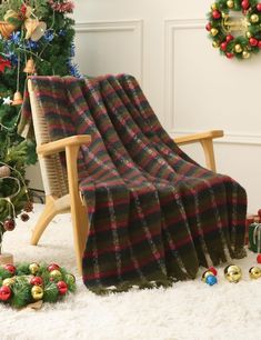 a chair with a plaid blanket on it in front of a christmas tree